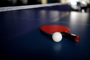 Tennis racket and ball on ping-pong table with net prepared for game