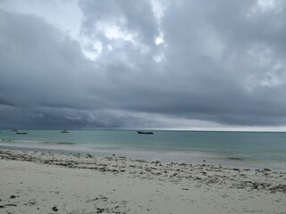 beach and boat in the horizon, grey sky about to rain, before the storm