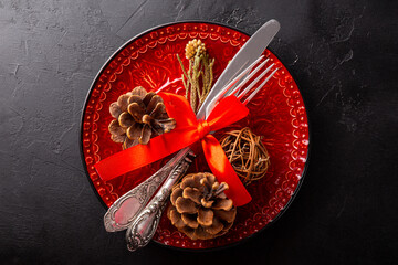 New Year and Christmas table setting concept. Black empty plate and silver cutlery with red...