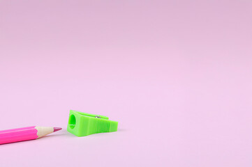 Pink pencil and green sharpener on a pink minimalist background.