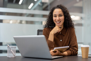 Confident woman with a notepad and laptop enjoying her work in a stylish office. The setting is informal yet professional, suggesting productivity, creativity, and modern workplace design.