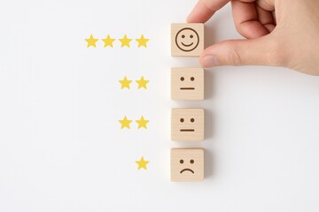Customer Satisfaction: A person's hand places a smiling face on a wooden block to indicate their customer satisfaction, next to star ratings.