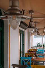 A restaurant with a lot of light fixtures hanging from the ceiling. The light fixtures are of different sizes and shapes, and they are all hanging from the ceiling. The restaurant has a lot of chairs