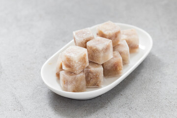 Meat jelly in the shape of a small cubes. On a ceramic plate	