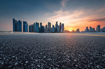 Empty asphalt road leading to a modern city skyline at sunset; warm-toned sky, dark-glass skyscrapers, vast expanse of road