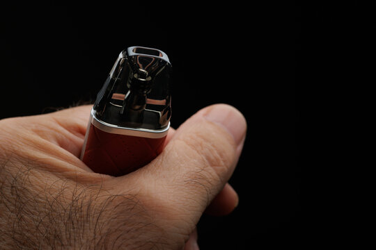 Mano de persona no reconocible sujeta cigarrillo electr&oacute;nico con fondo negro