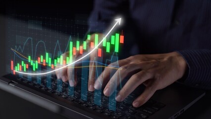 Business professional typing on laptop with stock market data visualization. The upward graph signifies growth and financial success in modern analytics. Copula