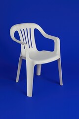 White plastic chair on bold blue background with minimal studio lighting
