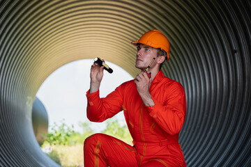 Engineers collaborate inside a massive steel pipe, constructing a tunnel for an industrial pipeline...