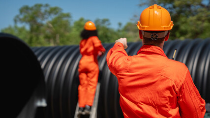 Engineers collaborate inside a massive steel pipe, constructing a tunnel for an industrial pipeline...
