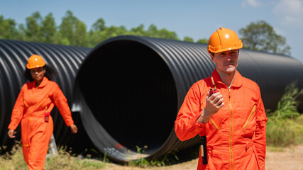 Engineers collaborate inside a massive steel pipe, constructing a tunnel for an industrial pipeline...