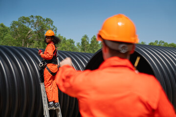 Engineers collaborate inside a massive steel pipe, constructing a tunnel for an industrial pipeline...