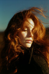 A woman with red hair is standing in the sun