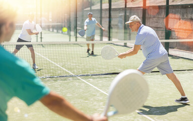Padel game - man with partners plays on tennis court