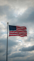 Obraz premium Waving American Flag Against a Backdrop of Soft, Cloudy Sky in a Tranquil Outdoor Setting During Daylight Hours