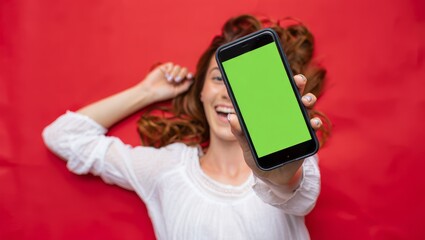 Happy Woman Showing Smartphone with Green Screen on Red Background