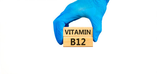 Vitamin B12 symbol. Concept words Vitamin B12 on beautiful wooden blocks. Doctor's hand in blue medical glove. Beautiful white background. Medical healthy lifestyle Vitamin B12 concept.