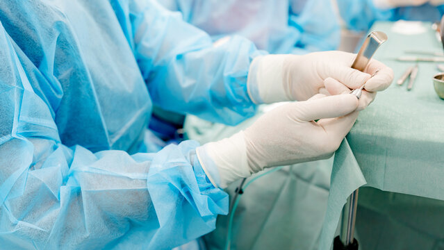 Close-up of a dentist in surgical gear preparing for implantology