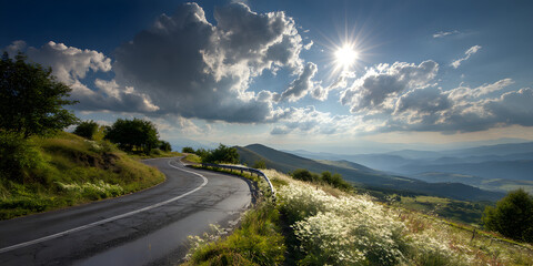 A winding paved road curves through a verdant landscape, leading towards a bright sun shining through fluffy clouds.