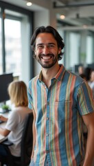 Obraz premium Cheerful man in a colorful shirt smiles warmly in a modern office setting