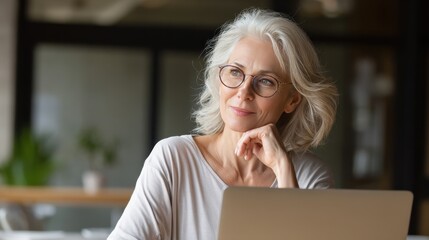 mature adult 60s aged woman working at laptop watching video conference webinar training virtual meeting business lady e learning online computer classes typing seniors and remote education no logos 