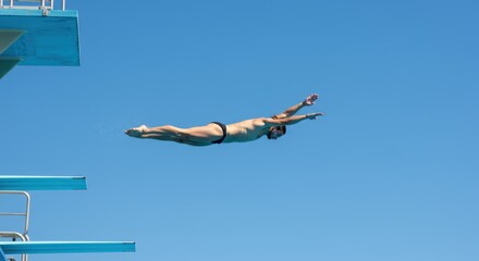 Diver leaps from high board into clear blue sky during summer training session