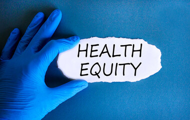 Health equity symbol. Concept words Health equity on beautiful white paper. Doctor's hand in blue...