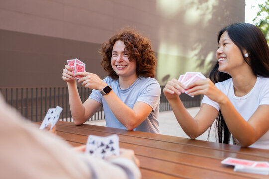 Multiethnic students playing cards outdoors