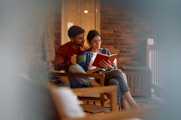 Happy couple reading book while relaxing on porch of their new home.