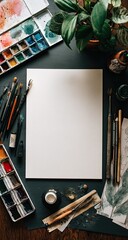 Flatlay of blank canvas surrounded by art supplies; paintbrushes, palettes, plant, papers