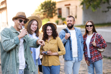 Fototapeta premium Guide with microphone and group of tourists on city street during excursion