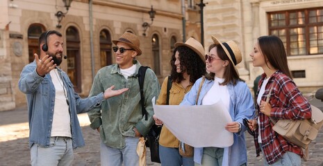 Guide with headset and group of tourists on city street during excursion