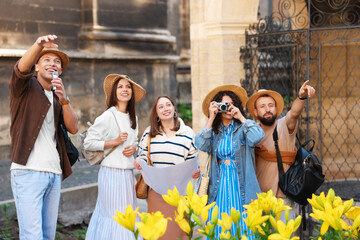 Guide with microphone and group of tourists on city street during excursion