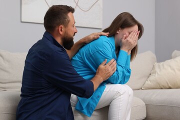 Obraz premium Betrayal. Husband apologizing to his crying wife on sofa at home