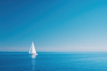 Obraz premium Sailboat glides across calm blue ocean under clear sky, embodyin