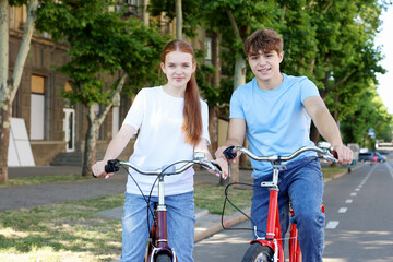 Obraz premium Teenage girl and boy riding bicycles on city street