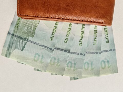 Currency notes, UAE Emirates currency 10 aed Dirhams, Closeup of UAE Ten dirhams currency notes, paper money 10 aed dirhams. Brown leather wallet with 10 dirhams banknotes, UAE Emirati 10 aed notes
