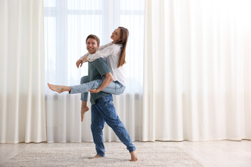 Happy young couple dancing together at home