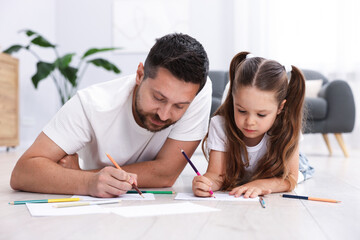 Father and his daughter drawing together on warm floor at home. Heating system