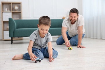 Father and his son playing with toys on warm floor at home, selective focus. Heating system