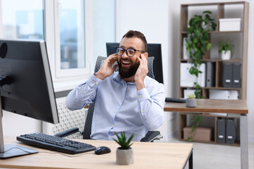 Man in glasses laughing at table in office