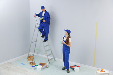 Woman with coffee and man on ladder renovating room