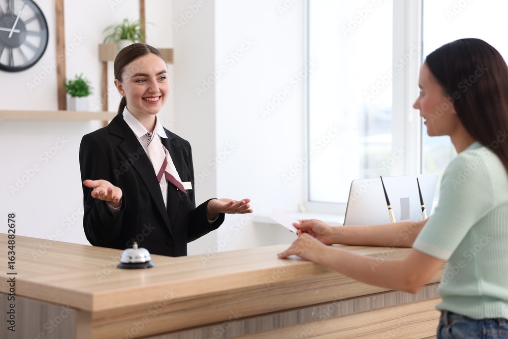 Aufkleber smiling receptionist working with guest at reception desk indoors