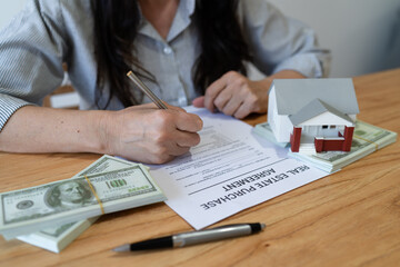 Woman buying a new home and signing the real estate purchase agreement.