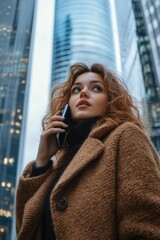 Woman talking on phone in front of modern skyscraper