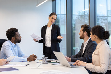 A group of professionals engaging in a dynamic discussion while reviewing documents and planning strategies together in a modern office setting, emphasizing teamwork, collaboration, and communication