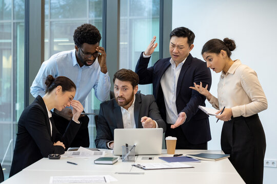 A diverse group of professionals engaged in a serious discussion around an office table.