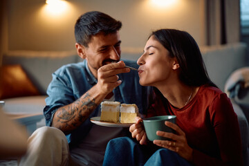 Young woman enjoying while tasting boyfriend's cake at home.