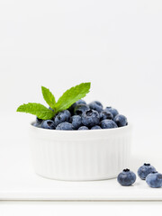 blueberries in a bowl, Bowl of fresh blueberries with mint on white board