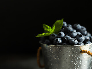 Blueberries with mint in a metal bucket on dark background